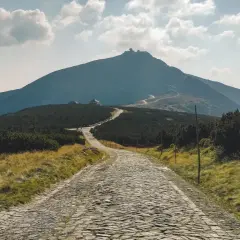 Kamienista droga prowadzi ku Śnieżce, najwyższej z gór w Karkonoszach, widocznej w oddali.