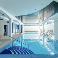 Relaks w spa nad morzem z basenem. Wnętrze z basenem, leżakami i niebieskimi akcentami.