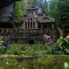 Kamienny domek w otoczeniu skał i zieleni, przypominający scenerię z Małej Szwajcarii Czech.