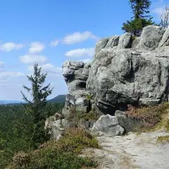 Narożnik Gór Stołowych z skalnymi formacjami i lasem w tle.