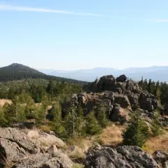 Góry Izerskie szczyty w oddali, skaliste zbocza i lasy iglaste na pierwszym planie.