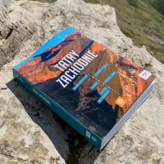 Przewodnik "Tatry Zachodnie" leży na kamieniach, gotowy do odkrywania górskich szlaków.