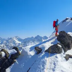 Wspinaczka zimą na Orlą Perć. Dwóch alpinistów na ośnieżonym szczycie, w tle majestatyczne Tatry.
