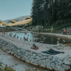 Relaks w gorących źródłach na Słowacji, blisko Bieszczad. Ludzie kąpią się w naturalnym basenie, otoczonym kamieniami i zielenią.