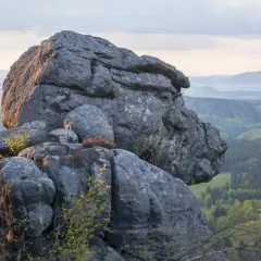 Imponujące formacje skalne na Górach Stołowych w Czechach, z widokiem na zielone doliny i wzgórza.