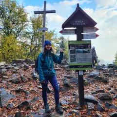 Kobieta na szczycie Łysicy, najniższej góry w Polsce (614 m n.p.m.). Jesień, liście, krzyż i drogowskazy.