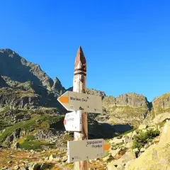 Szpiglasowy Wierch i Morskie Oko na drogowskazie. Skaliste szczyty Tatr pod błękitnym niebem.