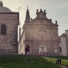 Para spaceruje po zielonym wzgórzu na tle zabytkowych budowli na łysą górę.