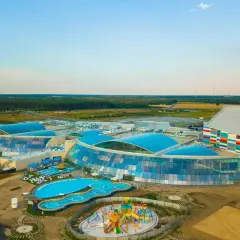 Największy aquapark w Polsce z błękitnymi dachami i kolorowym budynkiem. Widać baseny, zjeżdżalnie i plac zabaw.