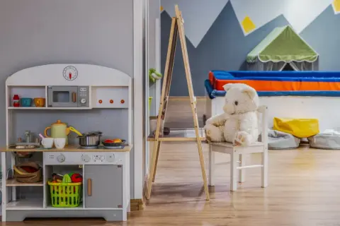 Uroczy pokój zabaw z kuchnią, pralką i pluszowym misiem. Idealne miejsce dla dzieci, jak w najlepszych hotelach dla dzieci.