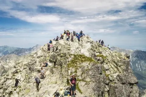 Tłum turystów na skalistym szczycie Rysów, najwyższego szczytu w Polsce. Widok na Tatry.