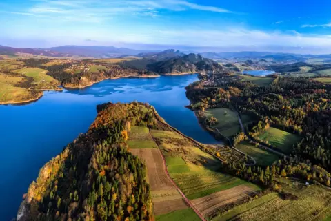 Malownicze jezioro otoczone jesiennymi lasami i polami. Idealne miejsce, by wybrać się gdzie nad jezioro.