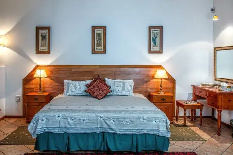 Przytulny pokój hotelowy z dużym łóżkiem, nocnymi stolikami i toaletką. Różne rodzaje pokoi hotelowych oferują komfort i styl.