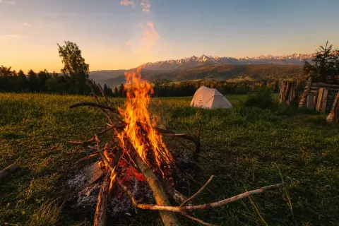 Ognisko i namiot na punkcie widokowym Łapszanka. W tle majestatyczne Tatry o zachodzie słońca.