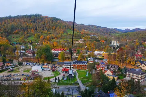 Widok z kolejki na palenice na jesienną dolinę pełną kolorowych drzew i zabudowań.