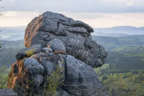 Imponujące formacje skalne na Górach Stołowych w Czechach, z widokiem na zielone doliny i wzgórza.