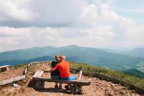 Para zakochanych na ławce podziwia bezkresne, zielone połoniny. Bieszczady jakie to góry – łagodne, rozległe, pełne spokoju.
