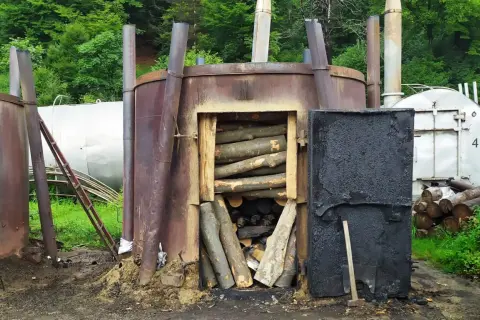 Wypał węgla drzewnego w Bieszczadach. Metalowe retorty z drewnem gotowym do przetworzenia.