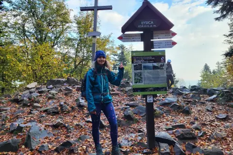 Kobieta na szczycie Łysicy, najniższej góry w Polsce (614 m n.p.m.). Jesień, liście, krzyż i drogowskazy.