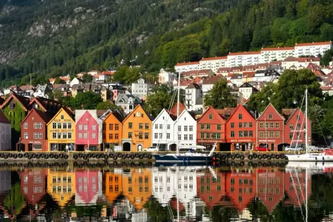 Kolorowe kamienice Bryggen w Bergen, wpisane na listę UNESCO, odbijają się w wodzie. Idealne miejsce, by zobaczyć, co oferuje to norweskie miasto.