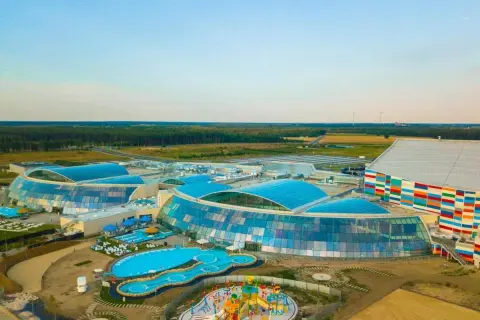 Największy aquapark w Polsce z błękitnymi dachami i kolorowym budynkiem. Widać baseny, zjeżdżalnie i plac zabaw.