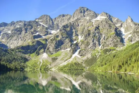 Morskie Oko, największe jezioro w Tatrach, odbija skaliste szczyty i zielone lasy w krystalicznie czystej wodzie.