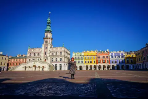 Kobieta na Rynku Wielkim w Zamościu, gdzie można zwiedzić renesansowy ratusz i kolorowe kamienice.