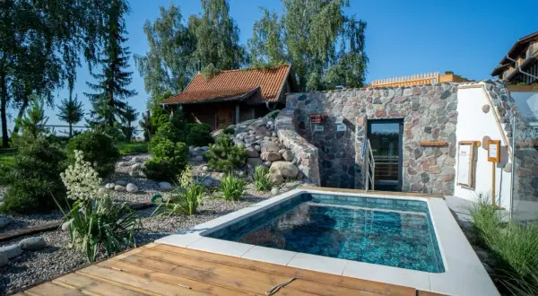 Relaks w klimatycznym spa w Polsce: basen, kamienna ściana z sauną i drewniany taras.