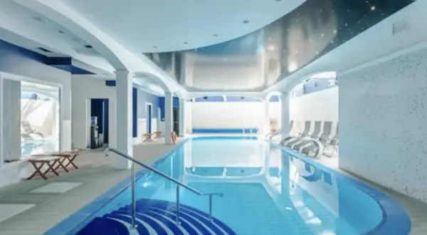 Relaks w spa nad morzem z basenem. Wnętrze z basenem, leżakami i niebieskimi akcentami.
