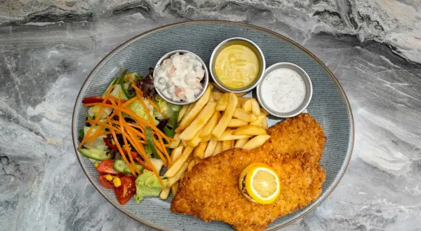 Pyszny panierowany kotlet z frytkami, surówką i sosami. Idealne miejsce, gdzie zjeść w Kołobrzegu, by poczuć smak morza.