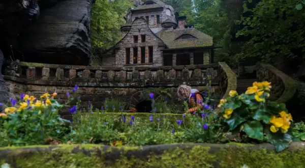 Kamienny domek w otoczeniu skał i zieleni, przypominający scenerię z Małej Szwajcarii Czech.