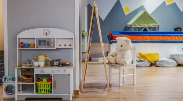 Uroczy pokój zabaw z kuchnią, pralką i pluszowym misiem. Idealne miejsce dla dzieci, jak w najlepszych hotelach dla dzieci.