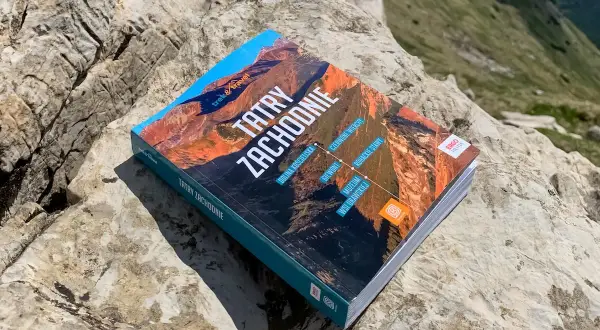 Przewodnik "Tatry Zachodnie" leży na kamieniach, gotowy do odkrywania górskich szlaków.