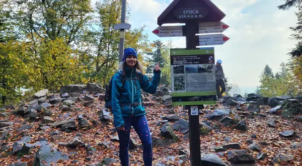 Kobieta na szczycie Łysicy, najniższej góry w Polsce (614 m n.p.m.). Jesień, liście, krzyż i drogowskazy.