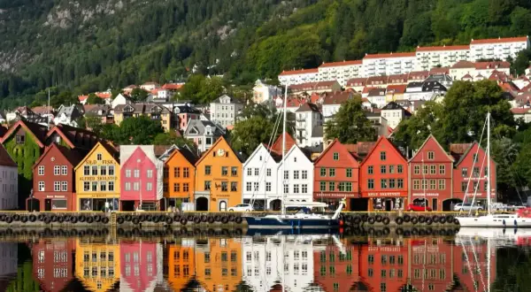 Kolorowe kamienice Bryggen w Bergen, wpisane na listę UNESCO, odbijają się w wodzie. Idealne miejsce, by zobaczyć, co oferuje to norweskie miasto.