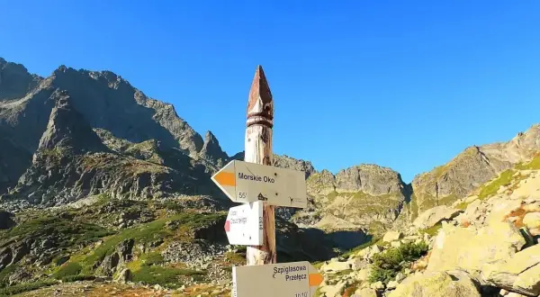 Szpiglasowy Wierch i Morskie Oko na drogowskazie. Skaliste szczyty Tatr pod błękitnym niebem.