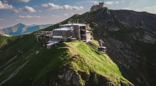 Kasprowy Wierch widok ze szczytu. Kolejka linowa wjeżdża na szczyt, gdzie znajdują się budynki obserwatorium i stacji meteorologicznej.