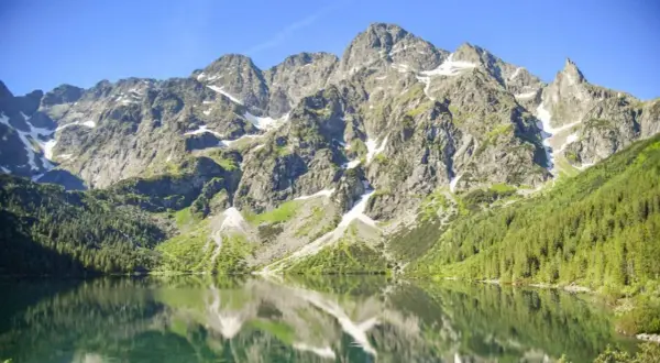 Morskie Oko, największe jezioro w Tatrach, odbija skaliste szczyty i zielone lasy w krystalicznie czystej wodzie.