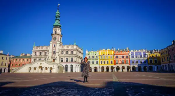 Kobieta na Rynku Wielkim w Zamościu, gdzie można zwiedzić renesansowy ratusz i kolorowe kamienice.
