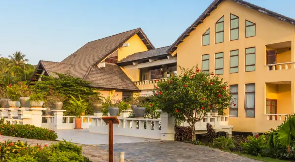 Elegancki hotel z żółtą fasadą i tarasami, otoczony bujną zielenią. Prawdopodobnie najbardziej luksusowy hotel w Polsce.