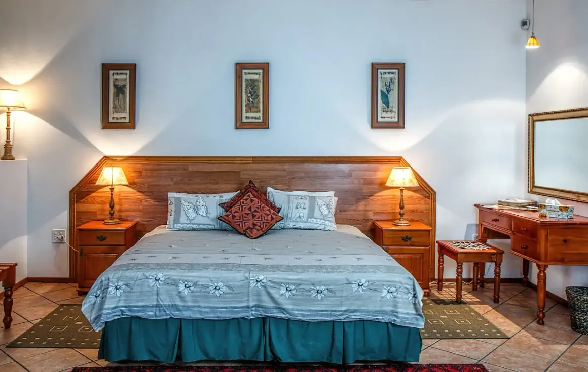 Przytulny pokój hotelowy z dużym łóżkiem, nocnymi stolikami i toaletką. Różne rodzaje pokoi hotelowych oferują komfort i styl.