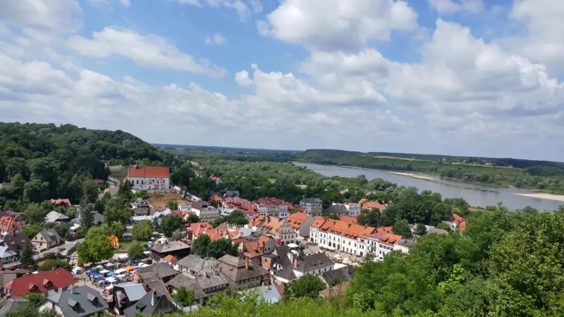 Widok na miasteczko z rzeką i wzgórzem. W oddali majaczy góra Trzech Krzyży.