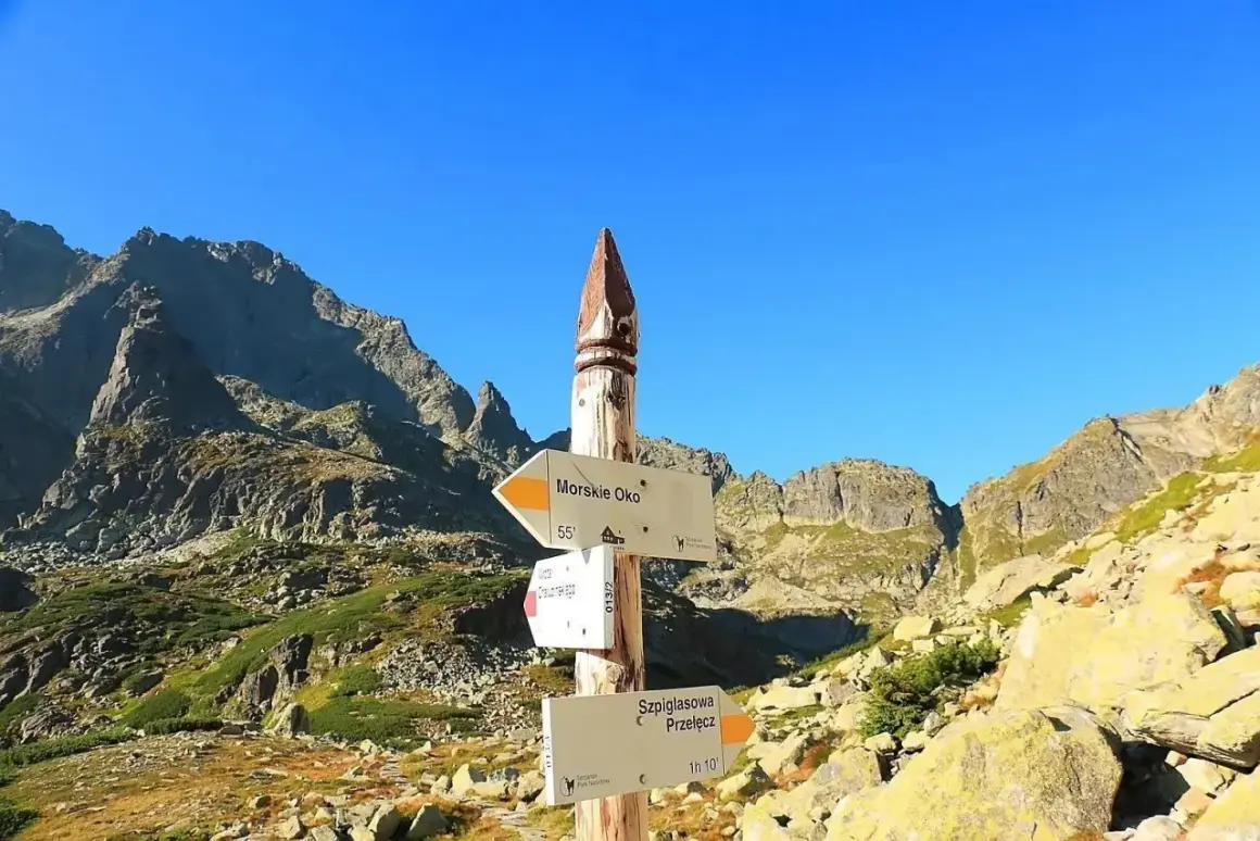 Szpiglasowy Wierch i Morskie Oko na drogowskazie. Skaliste szczyty Tatr pod błękitnym niebem.
