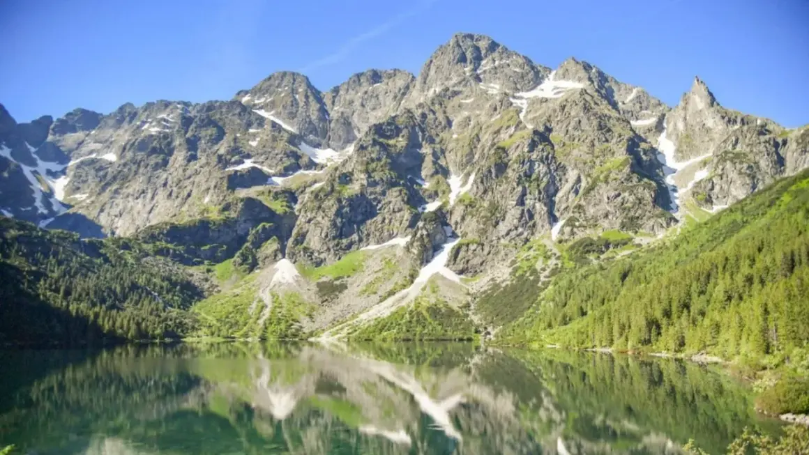Morskie Oko, największe jezioro w Tatrach, odbija skaliste szczyty i zielone lasy w krystalicznie czystej wodzie.