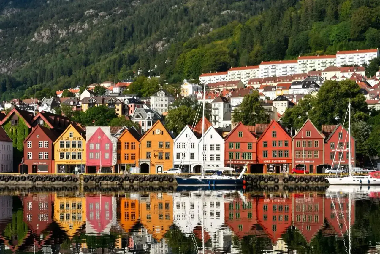 Kolorowe kamienice Bryggen w Bergen, wpisane na listę UNESCO, odbijają się w wodzie. Idealne miejsce, by zobaczyć, co oferuje to norweskie miasto.