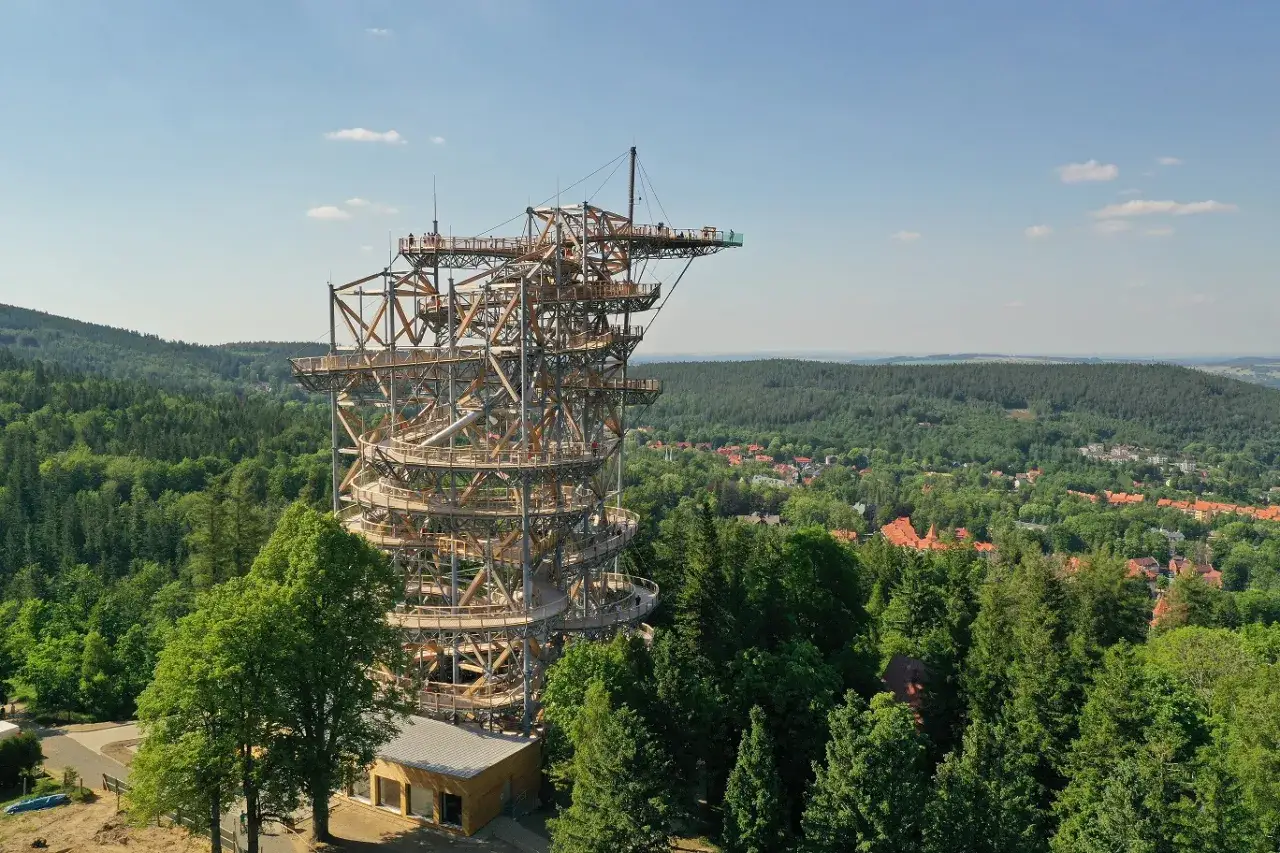 Drewniana konstrukcja Sky Walk w Świeradowie-Zdroju wznosi się ponad lasem, oferując widok na okoliczne wzgórza i miasteczko.