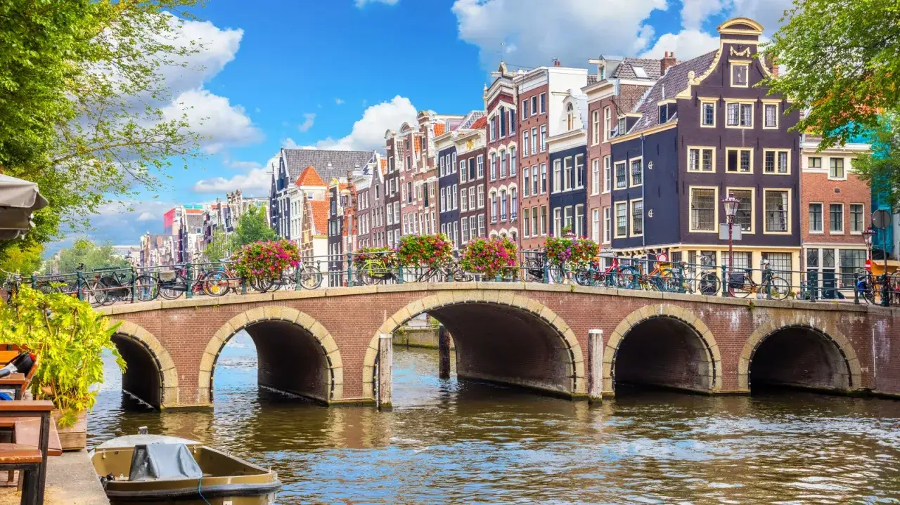 Amsterdam, jeden z najładniejszych miast w Europie, z kanałem, mostem i charakterystycznymi kamienicami.
