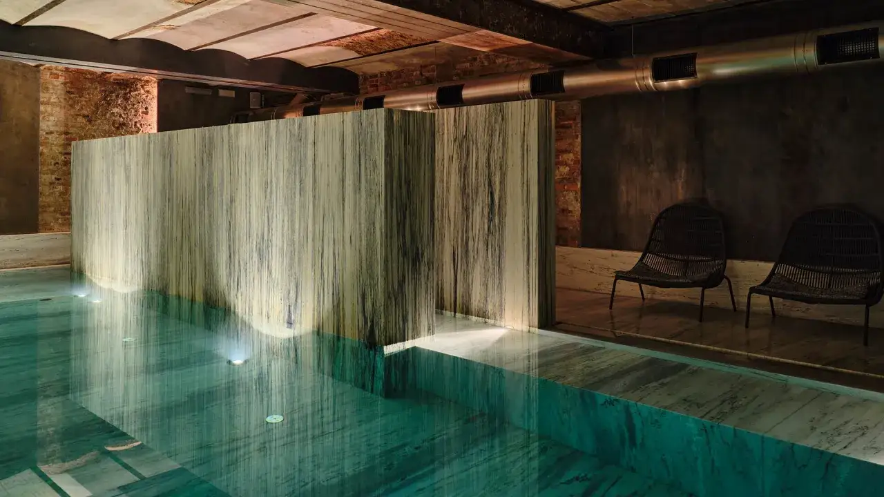 Klimatyczne spa w Polsce z basenem i kamiennymi ścianami. Dwa fotele w stylu boho czekają na gości.