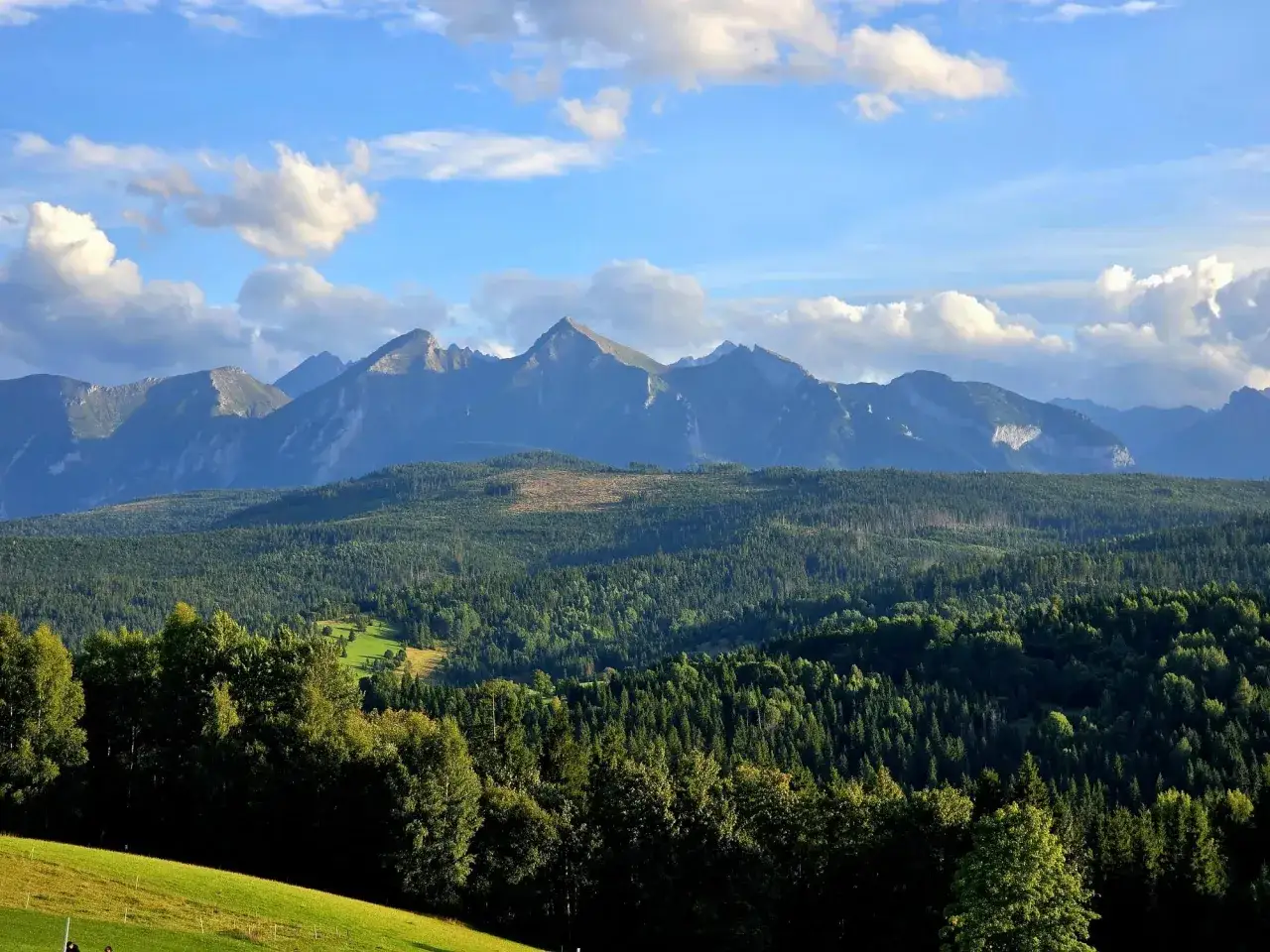 Widok z łapszanka punkt widokowy na Tatry. Zielone lasy i łąki pod błękitnym niebem z chmurami.