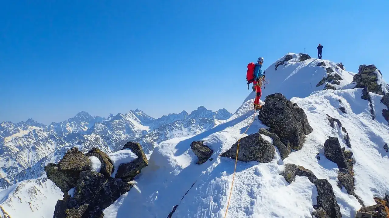 Alpinista na Orlej Perci zimą, wspinaczka po ośnieżonych skałach.